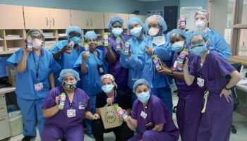 Healthcare workers holding beverages, supported by FOOD1st to aid NYC emergency services and food service workers.