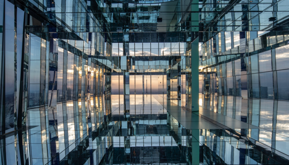 Reflective surfaces and mirrored walls in a modern interactive art exhibit in NYC at sunset.
