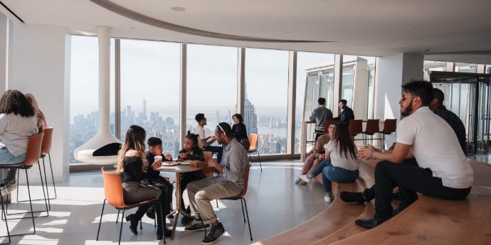 People enjoying food and drinks at Après café with views of the New York City skyline.