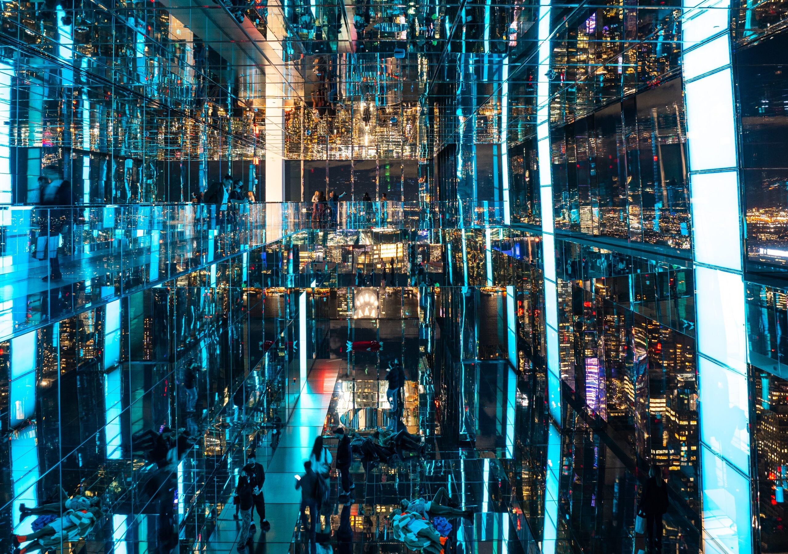 Visitors walking through the mirrored space at SUMMIT One Vanderbilt, surrounded by vibrant city reflections.