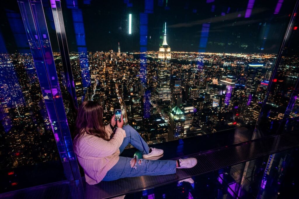 Guest leaning on reflective wall overviewing New York City