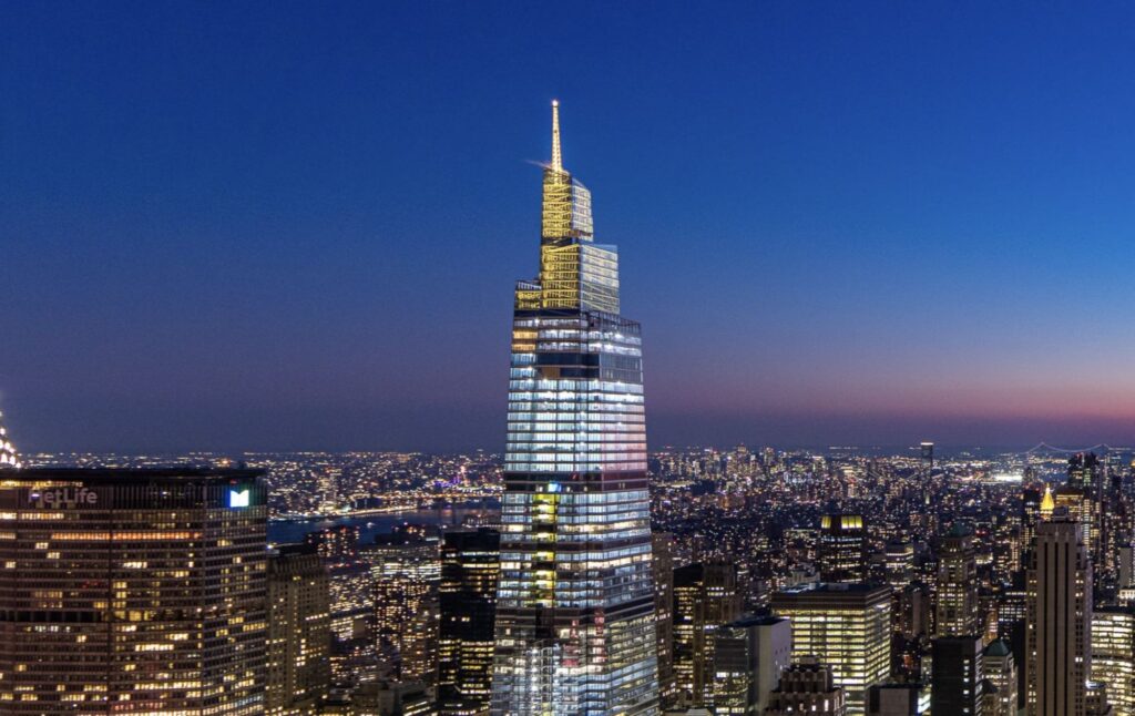 SUMMIT One Vanderbilt illuminated at night against the New York City skyline.